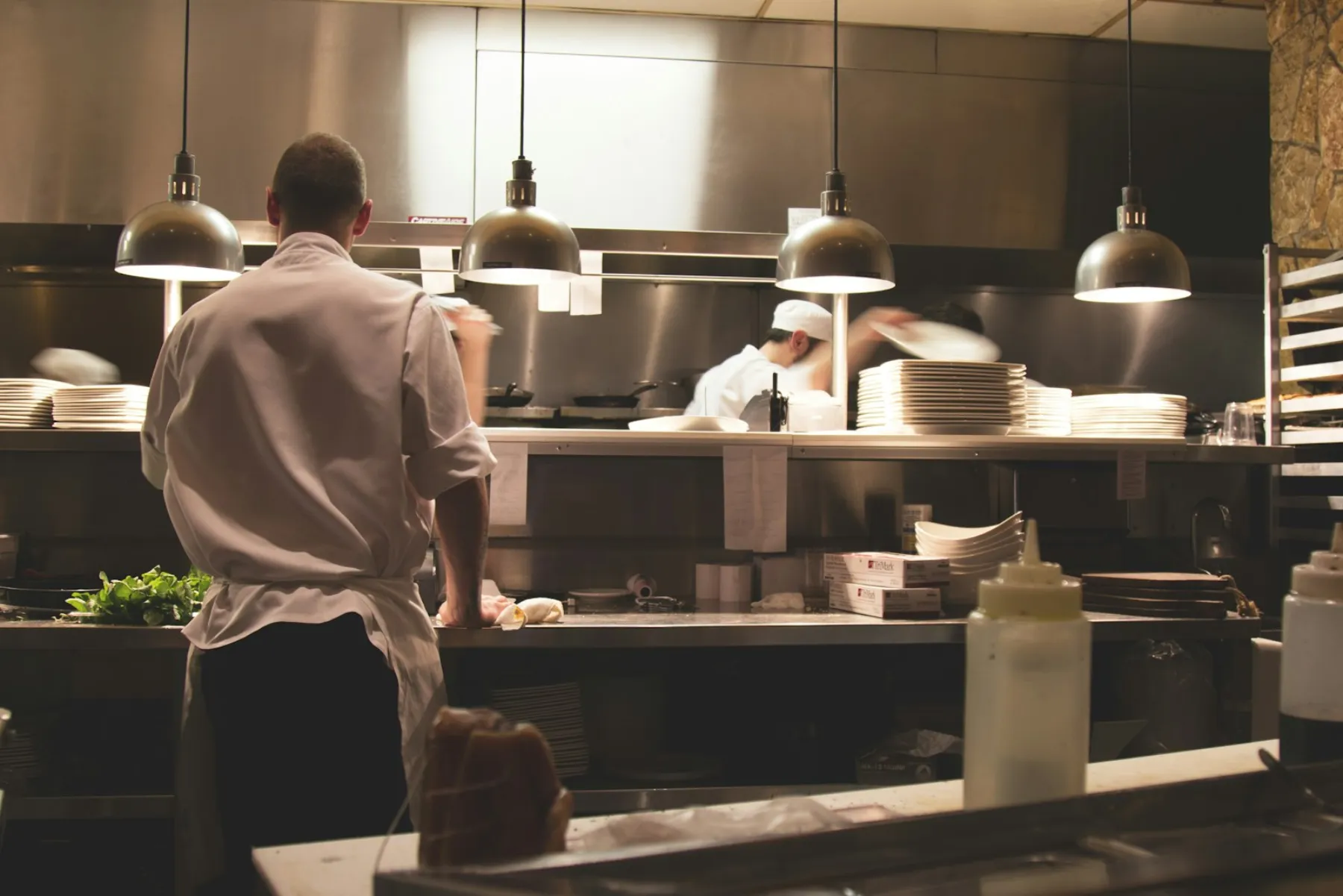 Chefs working the pass in a restaurant kitchen under warm lights